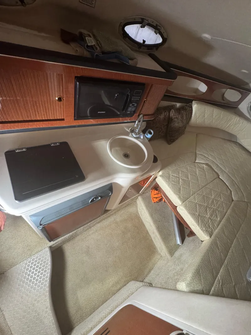 Slide: The Image of 2004 Sea Ray 260 Sundancer cabin interior with kitchenette and seating area. - 16
