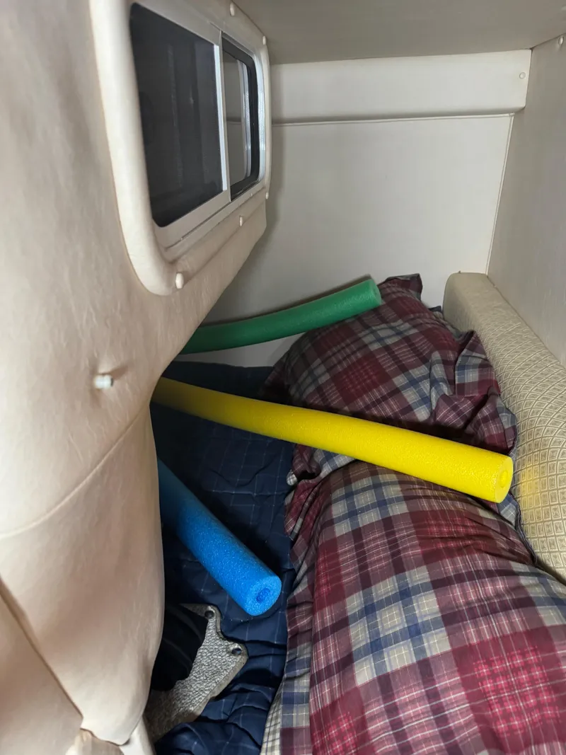 Slide: The Image of Interior cabin of 2004 Sea Ray 260 Sundancer with pool noodles and plaid bedding. - 20
