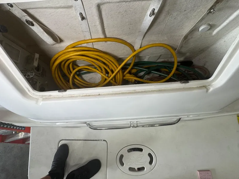 Slide: The Image of Storage compartment of a 2004 Sea Ray 260 Sundancer with coiled yellow hose. - 25