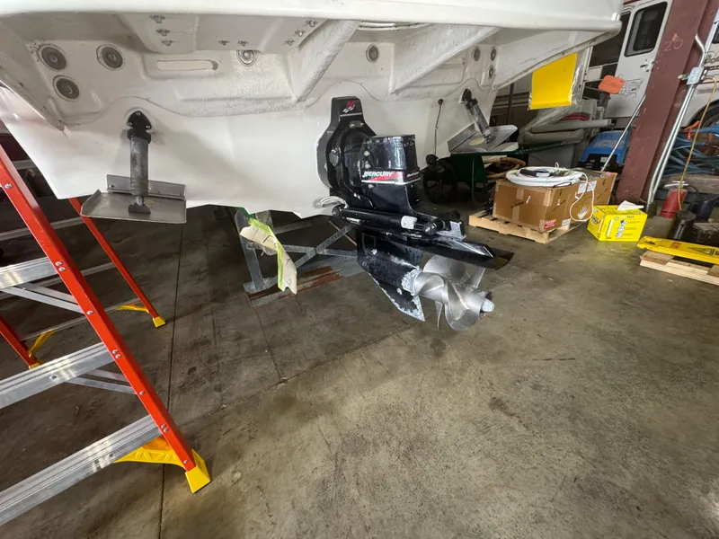 Slide: The Image of 2004 Sea Ray 260 Sundancer boat in a workshop, showing the propeller and stern drive. - 26