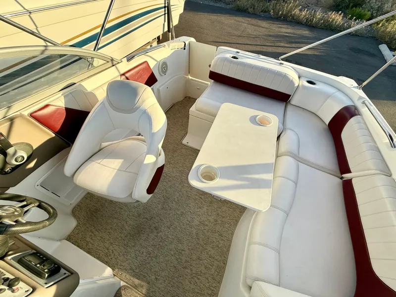 Slide: The Image of 2013 Ebbtide 2500 SS Fun Cruiser DC interior with white and red seating, table, and steering wheel. - 14