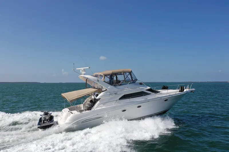 Slide: The Image of 2001 Sea Ray 450 Express Bridge yacht cruising on open water under clear blue sky. - 0