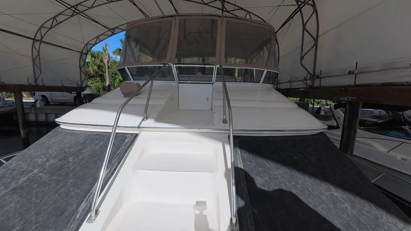 Slide: The Image of 2001 Sea Ray 450 Express Bridge yacht under canopy, front view with stairs and railing. - 13