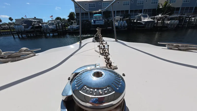 Slide: The Image of Bow view of 2001 Sea Ray 450 Express Bridge at marina, showcasing anchor chain and winch. - 15