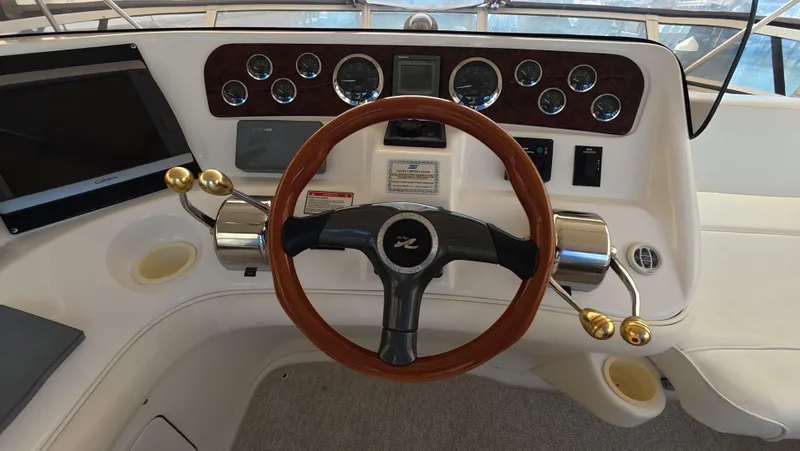 Slide: The Image of 2001 Sea Ray 450 Express Bridge helm with wood steering wheel and control panel. - 19
