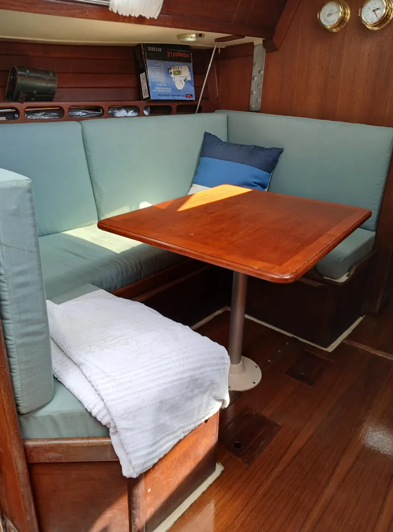 Slide: The Image of Cozy Ericson 30+ 1988 sailboat interior with wooden table and cushioned seating. - 10