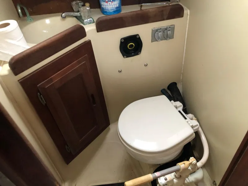 Slide: The Image of 1988 Ericson 30+ boat bathroom with toilet, sink, and wooden cabinet. - 15