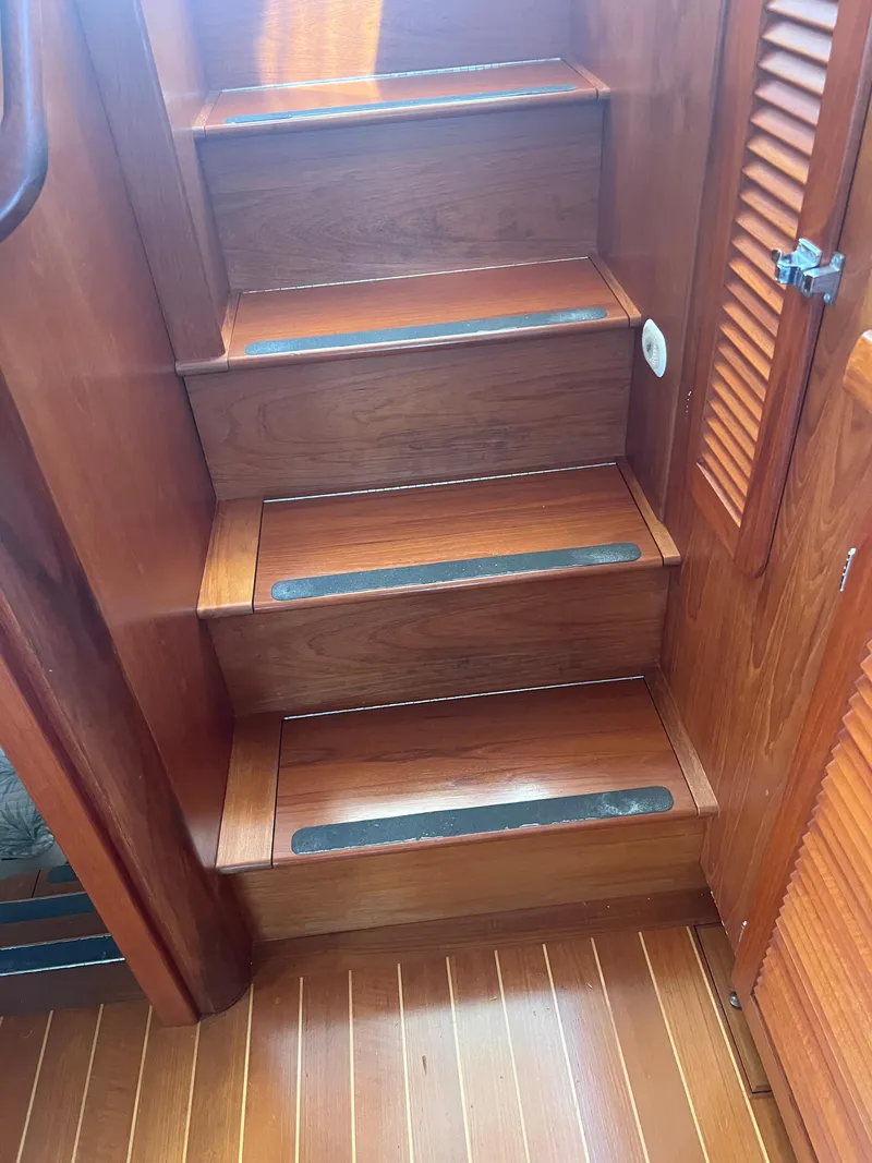 Slide: The Image of Wooden stairs inside a 1998 Cherubini Independence boat, featuring non-slip strips. - 48