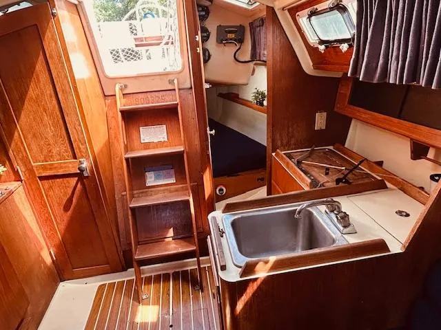 Slide: The Image of Interior of a 1986 Pearson 28 sailboat with wooden cabinetry and compact kitchen area. - 11