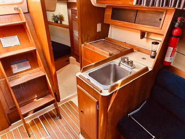 Slide: The Image of Interior of 1986 Pearson 28 sailboat with wooden cabinetry and compact kitchen area. - 12