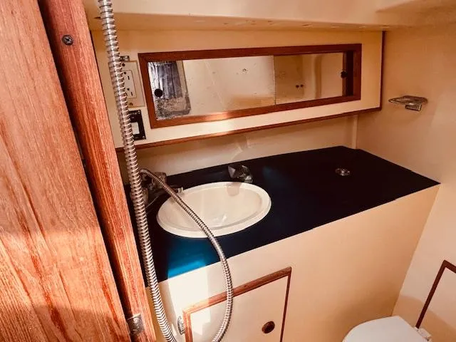 Slide: The Image of 1986 Pearson 28 yacht bathroom with sink, mirror, and wooden accents. - 17