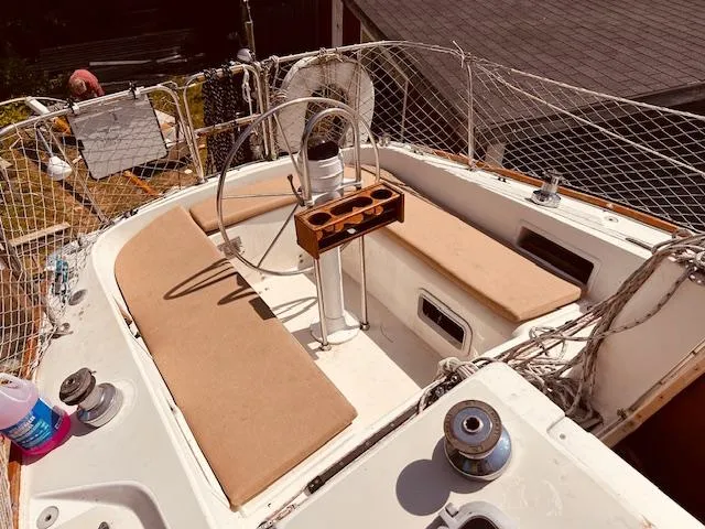 Slide: The Image of 1986 Pearson 28 sailboat cockpit with beige cushions and steering wheel, featuring a wooden cup holder. - 2