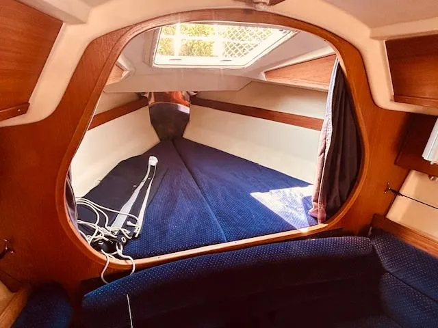 Slide: The Image of Cozy interior of a 1986 Pearson 28 sailboat with blue upholstery and wooden accents. - 20