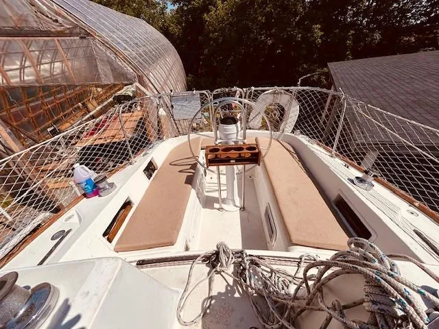 Slide: The Image of 1986 Pearson 28 sailboat deck with seating, ropes, and netting in a sunny setting. - 4