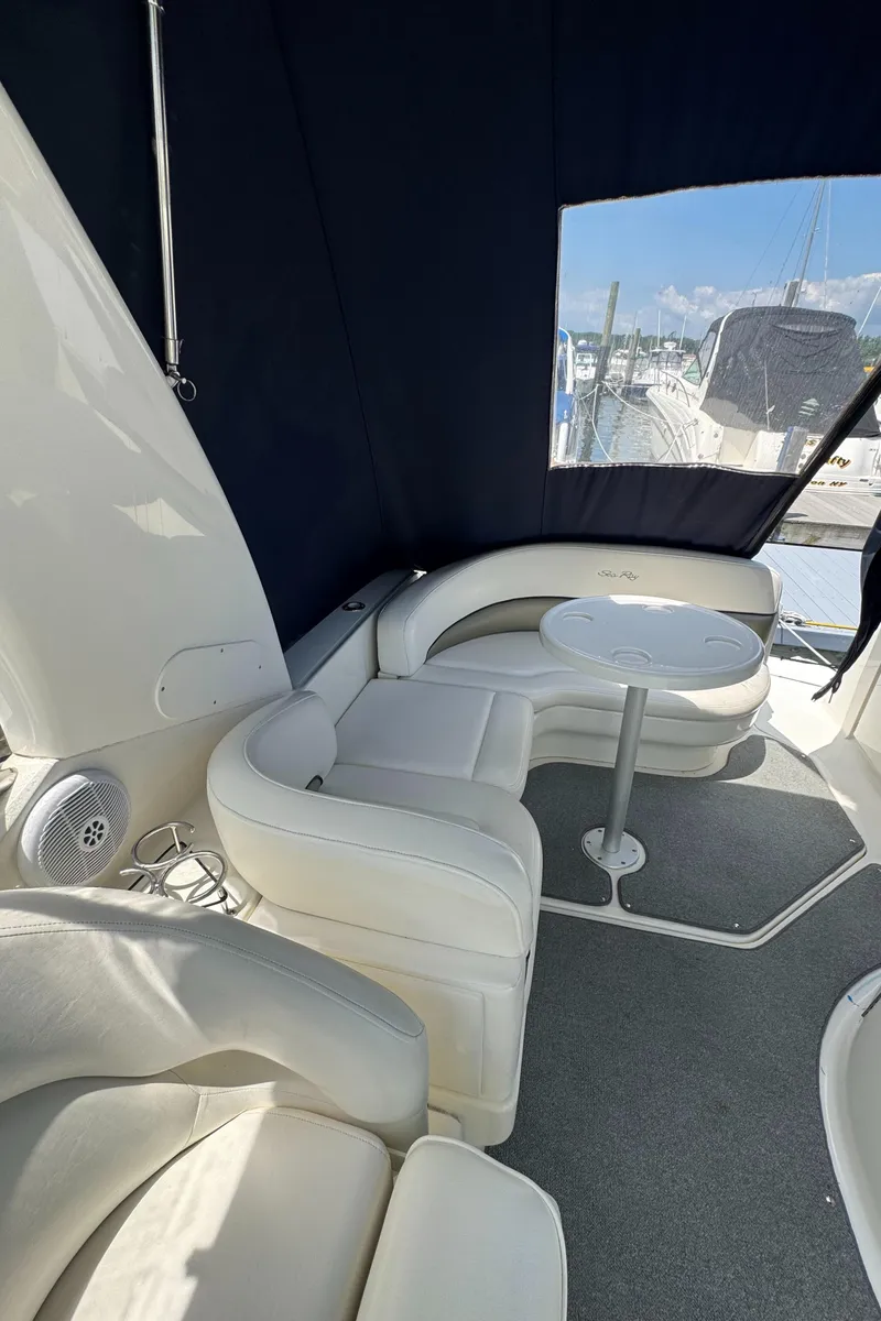 Slide: The Image of 2005 Sea Ray 260 Sundancer interior with white seating and table, docked at marina. - 10