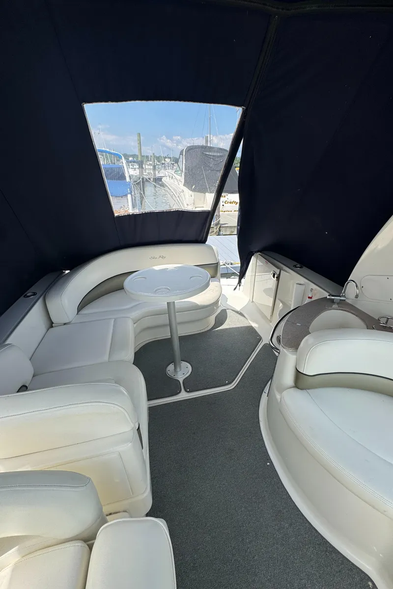 Slide: The Image of Interior of 2005 Sea Ray 260 Sundancer with white seating and table, marina view. - 12