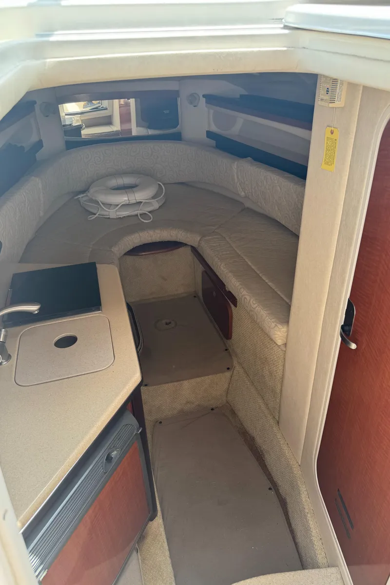 Slide: The Image of Interior of a 2005 Sea Ray 260 Sundancer boat, featuring a compact cabin with seating and kitchenette. - 20