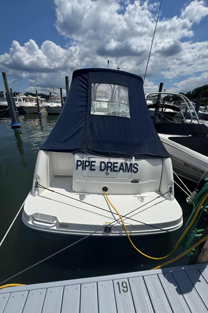 Slide: The Image of 2005 Sea Ray 260 Sundancer boat named "Pipe Dreams" docked at marina under cloudy sky. - 3