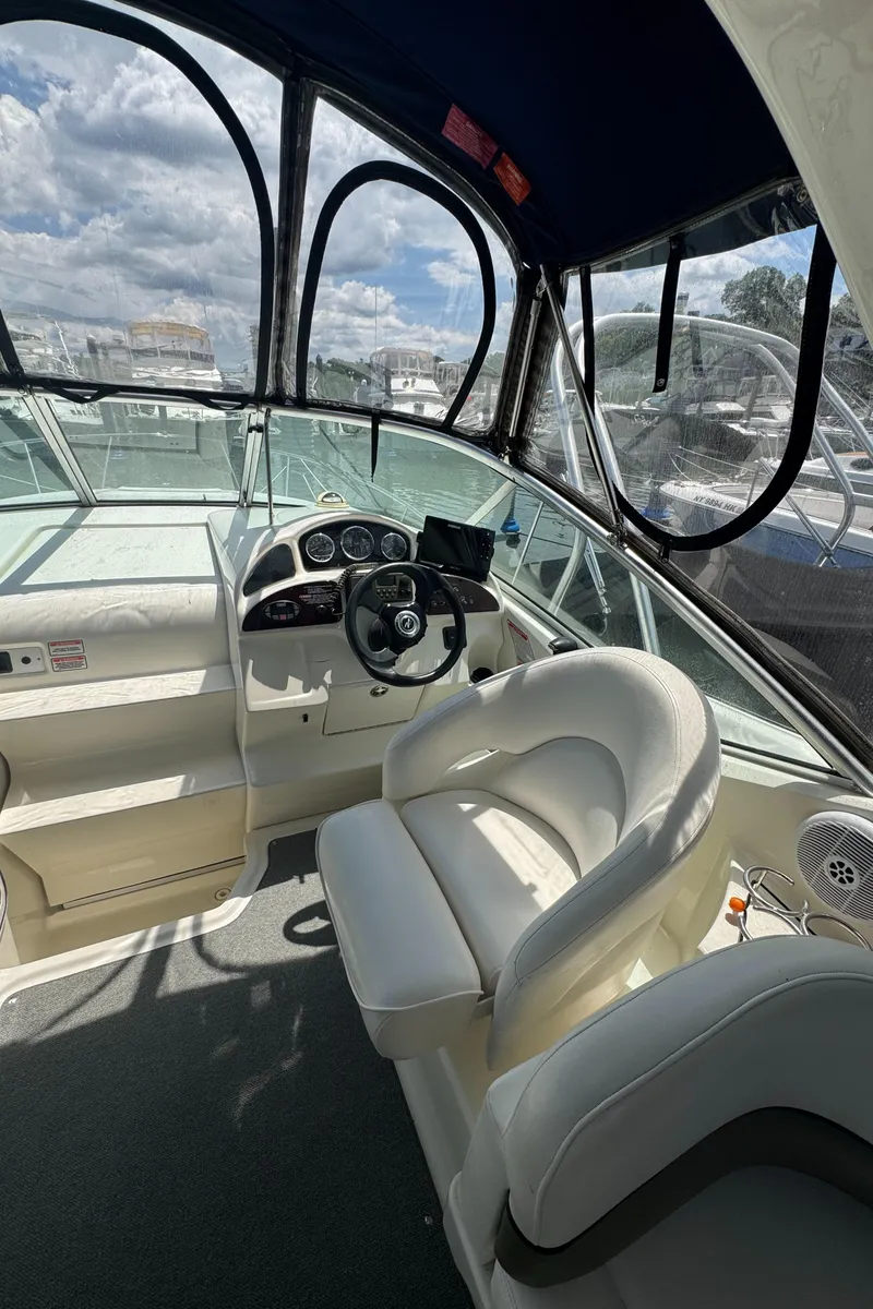 Slide: The Image of 2005 Sea Ray 260 Sundancer boat interior with steering wheel and seating under a clear canopy. - 6