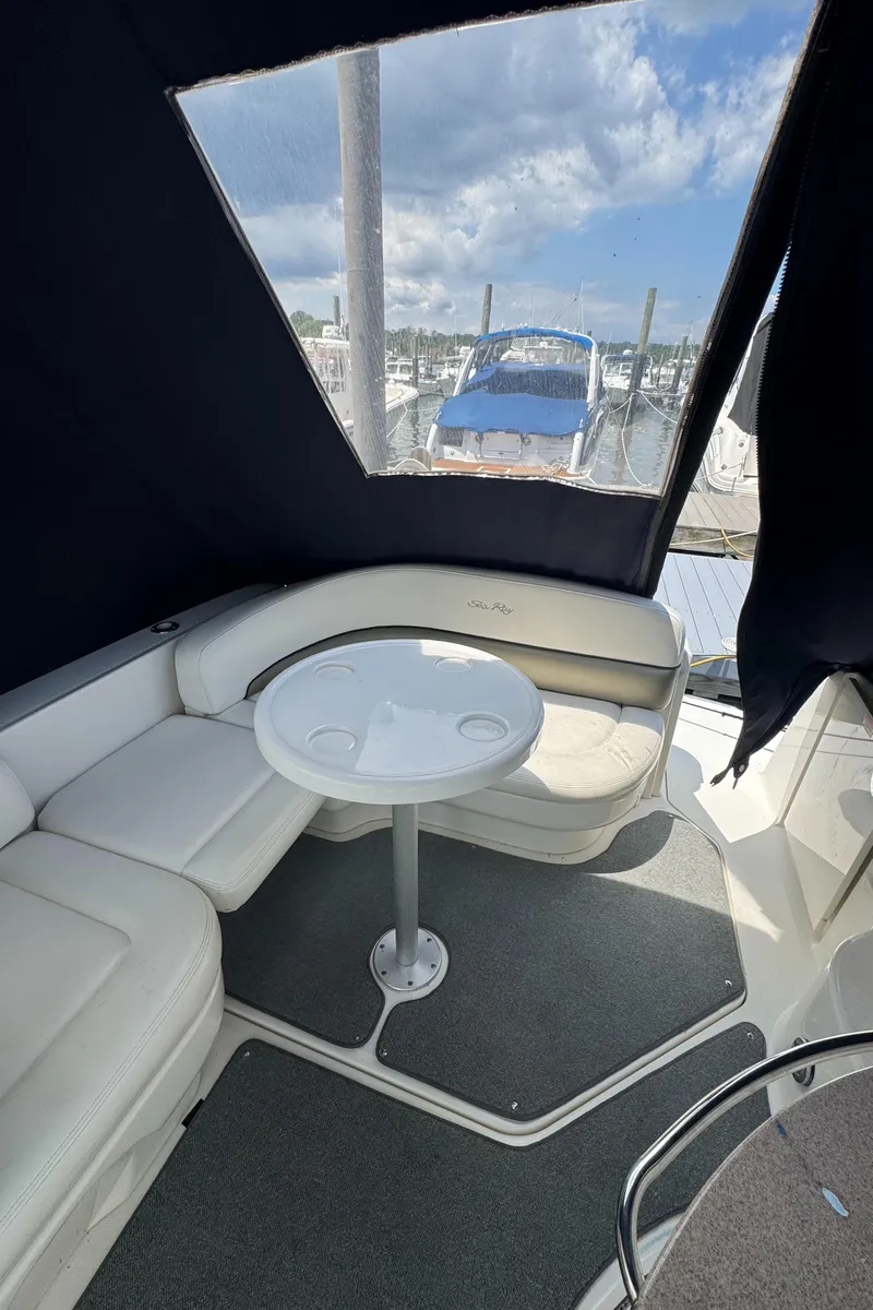 Slide: The Image of 2005 Sea Ray 260 Sundancer interior with seating and table, docked at marina. - 8