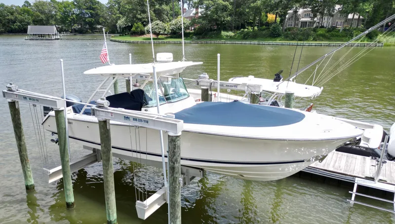 Slide: The Image of 2014 Pursuit ST 310 Sport boat docked on a lift by a serene lake. - 13