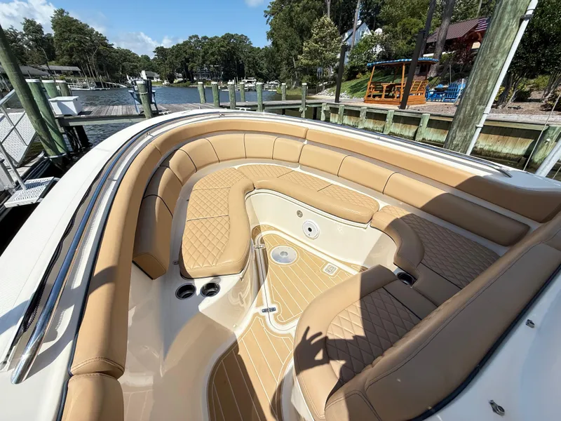 Slide: The Image of 2014 Pursuit ST 310 Sport boat with tan seating, docked by a scenic waterfront. - 14