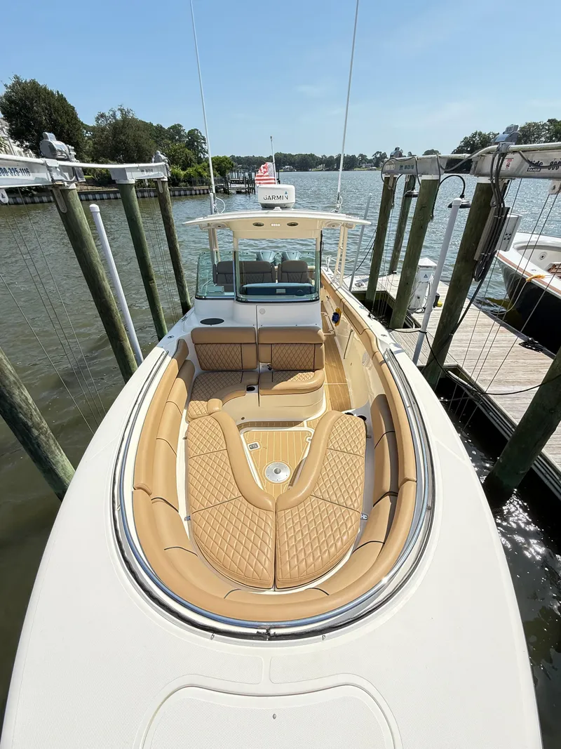Slide: The Image of 2014 Pursuit ST 310 Sport boat with tan seating, docked by a scenic waterfront. - 15