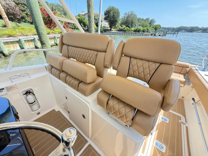 Slide: The Image of Luxurious seating on 2014 Pursuit ST 310 Sport boat, featuring tan leather upholstery and scenic waterfront view. - 18