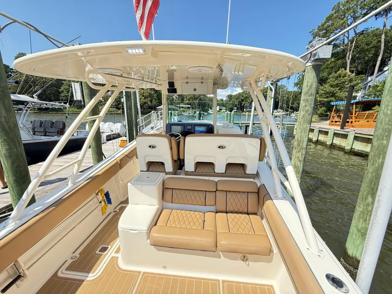 Slide: The Image of 2014 Pursuit ST 310 Sport boat interior with tan seating and helm, docked at marina. - 20