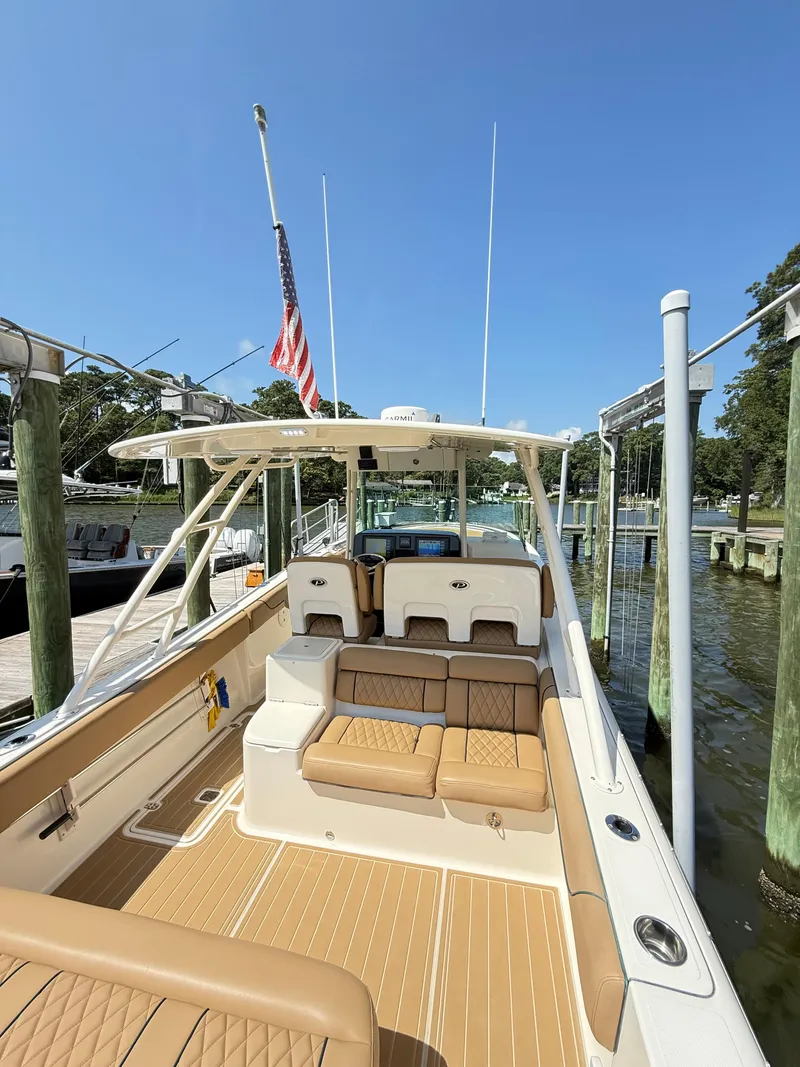 Slide: The Image of 2014 Pursuit ST 310 Sport boat docked, featuring tan seating and American flag. - 25