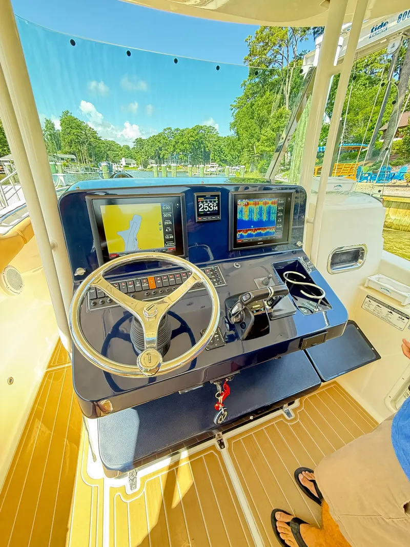 Slide: The Image of 2014 Pursuit ST 310 Sport boat helm with navigation screens and steering wheel. - 26