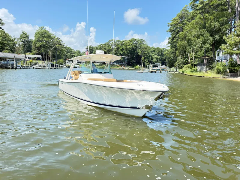 Slide: The Image of 2014 Pursuit ST 310 Sport boat on a sunny lake with lush green surroundings. - 3