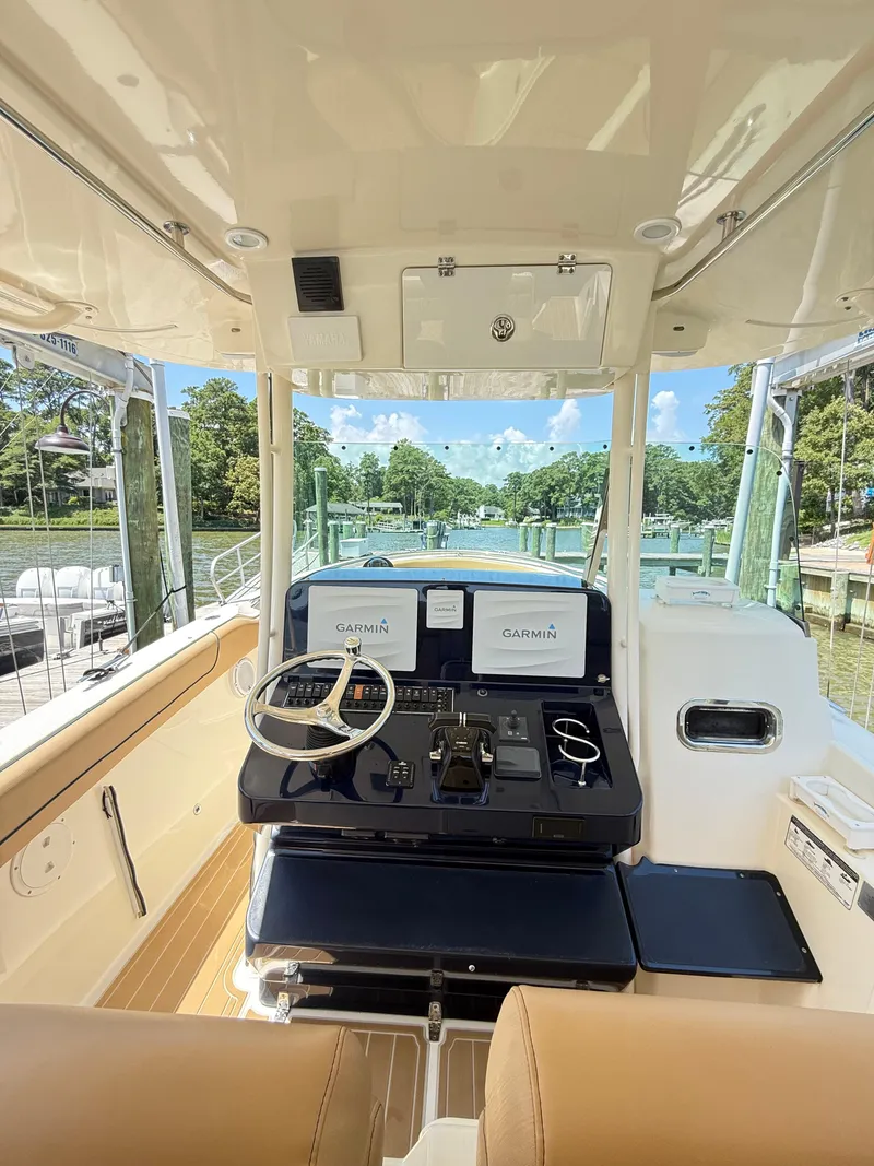 Slide: The Image of 2014 Pursuit ST 310 Sport boat interior with Garmin navigation, docked by a scenic waterfront. - 30