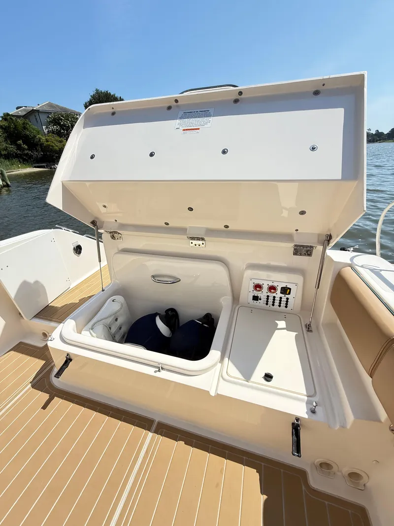 Slide: The Image of 2014 Pursuit ST 310 Sport boat storage compartment open by the water. - 37