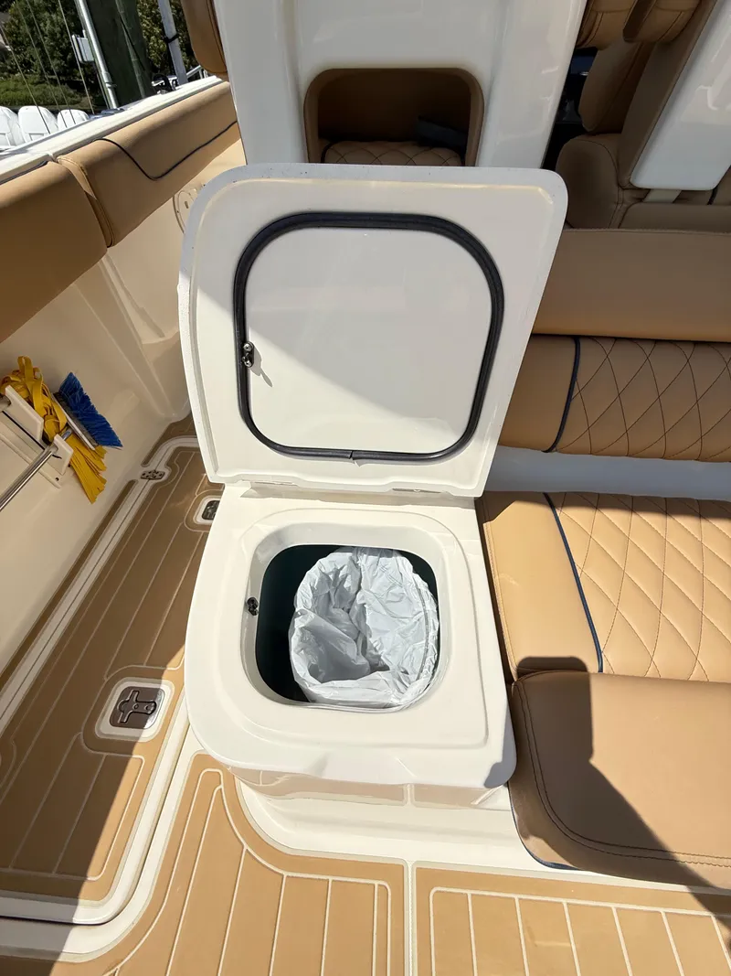 Slide: The Image of 2014 Pursuit ST 310 Sport boat interior with open storage compartment and tan seating. - 41