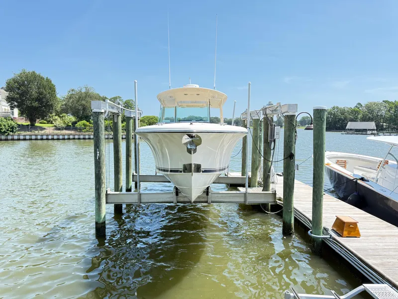 Slide: The Image of 2014 Pursuit ST 310 Sport boat docked on a lift by the water. - 8