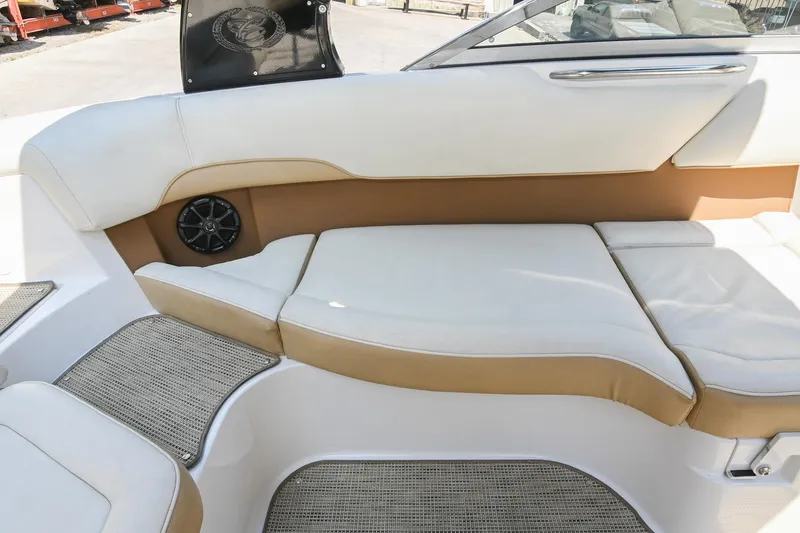 Slide: The Image of 2015 Cobalt 220 boat interior with white and tan seating, speaker, and carpeted flooring. - 19