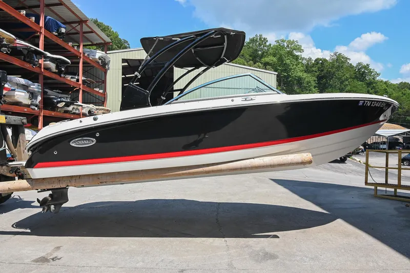 Slide: The Image of 2015 Cobalt 220 boat in storage, black and white with red stripe, outdoor setting. - 3