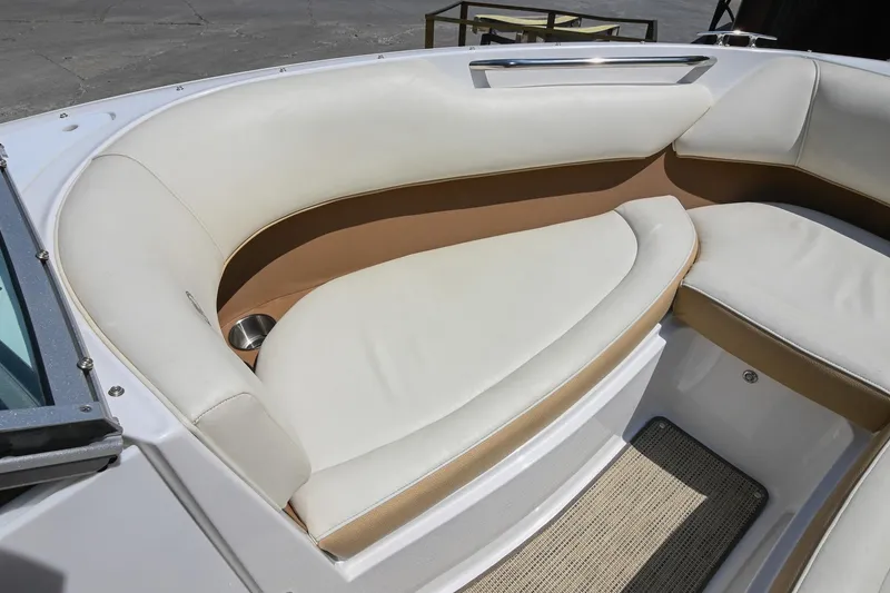 Slide: The Image of 2015 Cobalt 220 boat interior with white and tan seating, cup holder, and carpeted floor. - 33