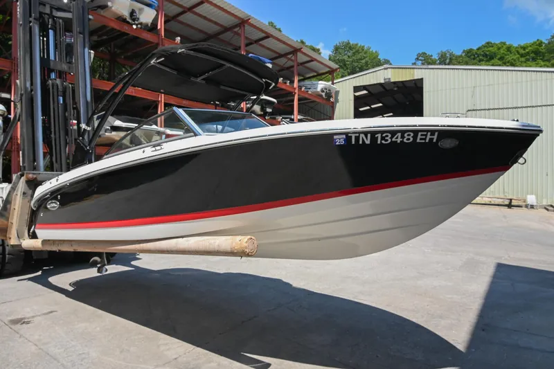Slide: The Image of 2015 Cobalt 220 boat on forklift, black hull with red stripe, stored outdoors. - 4