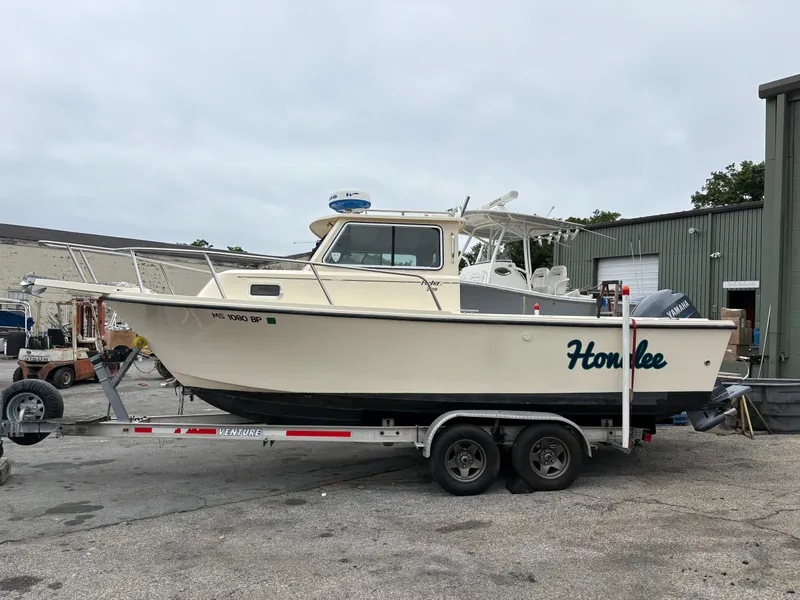 The Image of 2012 Parker 2120 Sport Cabin boat on trailer, parked outdoors near industrial building. - 0