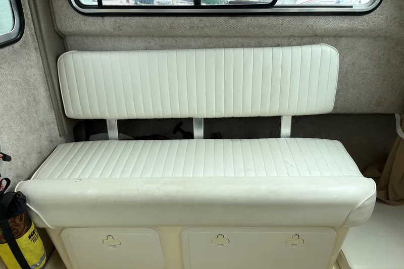 Slide: The Image of White cushioned bench seat inside a 2012 Parker 2120 Sport Cabin boat. - 17