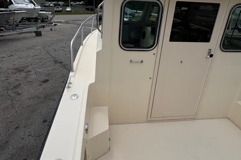 Slide: The Image of 2012 Parker 2120 Sport Cabin boat exterior with door and railing, parked on pavement. - 22