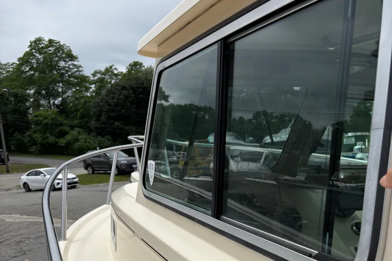 Slide: The Image of 2012 Parker 2120 Sport Cabin boat with reflective windows and railing, parked outdoors. - 24