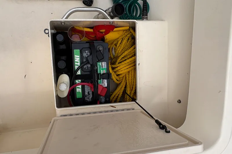 Slide: The Image of Boat storage compartment with battery, yellow rope, and cables in a 2012 Parker 2120 Sport Cabin. - 25