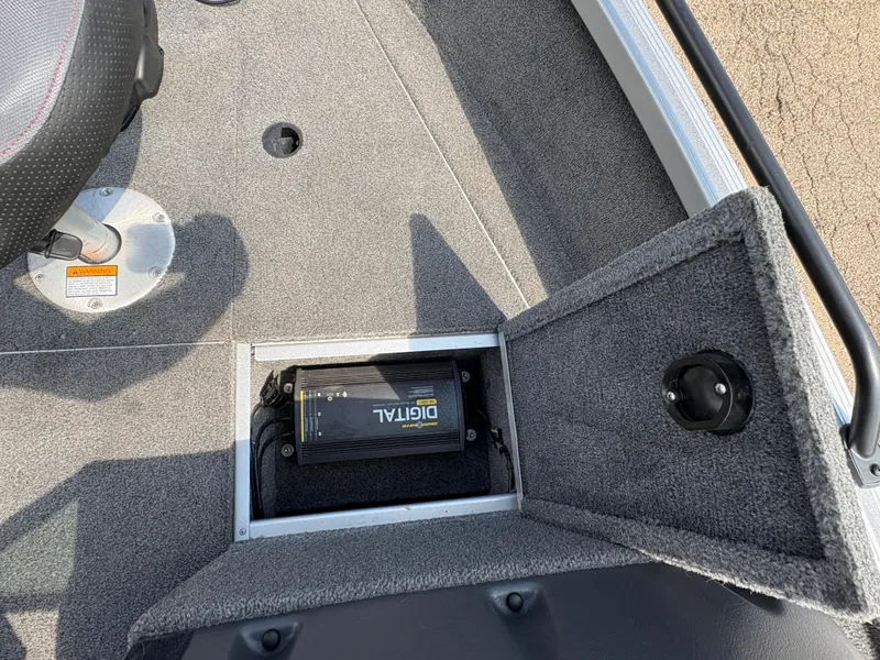 Slide: The Image of 2018 Alumacraft Voyageur 175 Sport boat interior with open storage compartment and digital charger. - 15