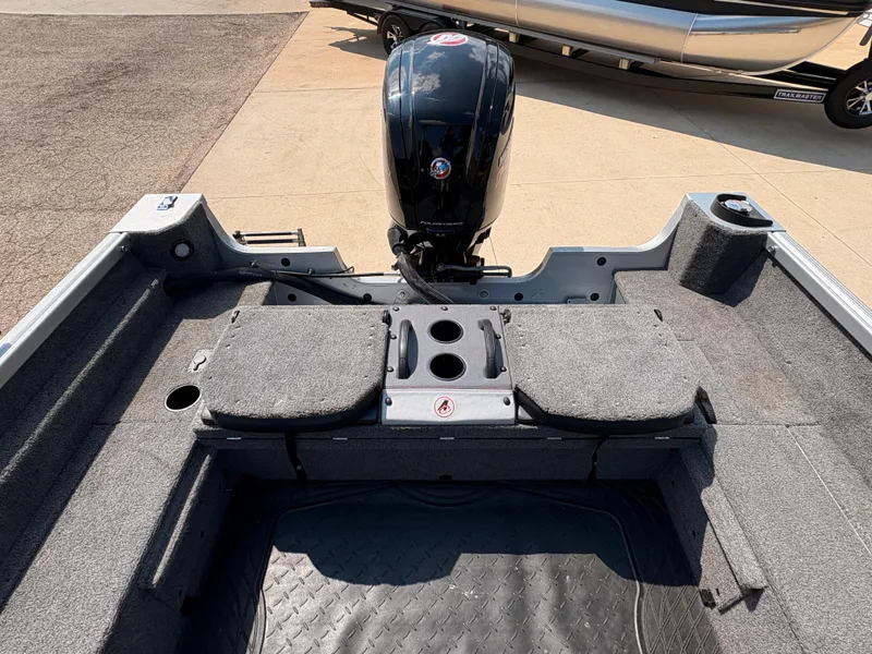 Slide: The Image of 2018 Alumacraft Voyageur 175 Sport boat interior with motor, gray carpet, and storage compartments. - 27