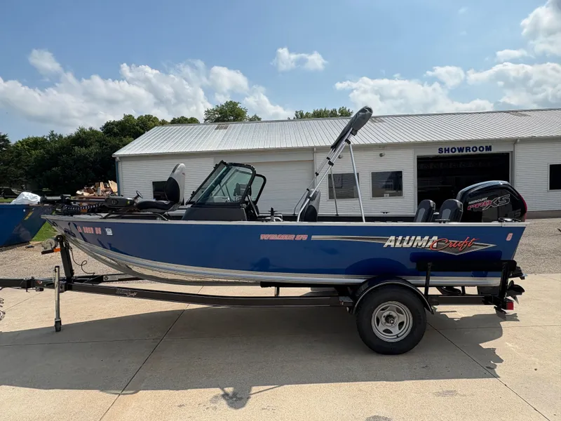 Slide: The Image of 2018 Alumacraft Voyageur 175 Sport boat on trailer outside showroom. - 6