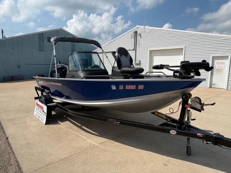 Slide: The Image of 2018 Alumacraft Voyageur 175 Sport boat on trailer, parked outside a building. - 9