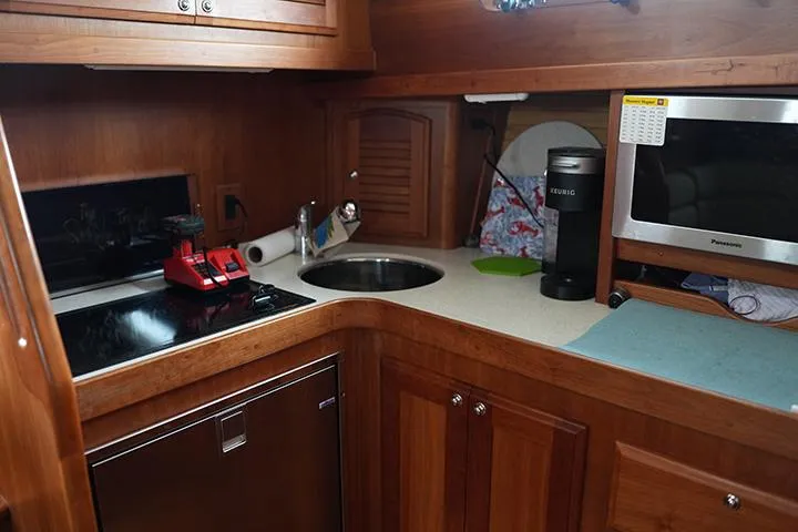 Slide: The Image of 2006 Sabre 38 Hardtop Express galley with wood cabinetry, sink, stove, and microwave. - 8